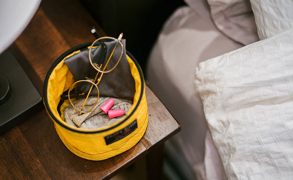 A Large Travel Tray holding a eyeglass cleaning rag, glasses, earplugs, and a handtowel.